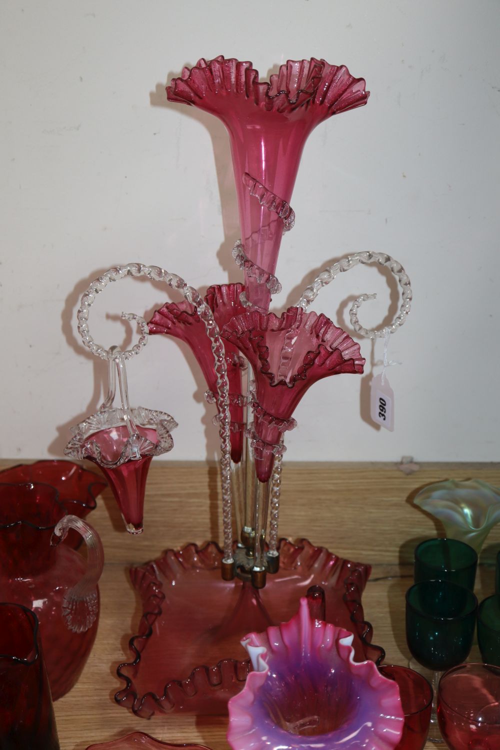 A Victorian cranberry glass epergne, height 56cm, a set of green glasses, two vaseline vases, etc